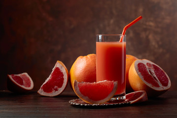 Glass of fresh grapefruit juice and cut fruits .