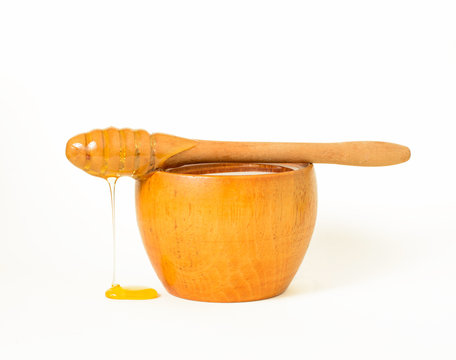 Honey in a wooden bowl and a honey dipper, a special kind of kitchen utensil used to collect honey from a vessel.