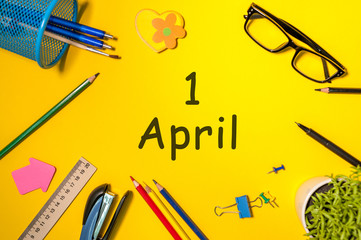 Fools day - April 1st. Day 1 of april month, calendar on yellow school desk background. Spring time