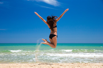 Happy woman in a jump on beach
