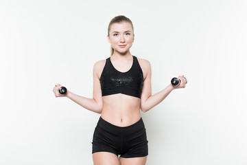 Young woman in sports top lifting dumbbells isolated on white