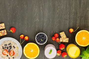Healthy breakfast of muesli, berries with yogurt and orange juice on dark background.