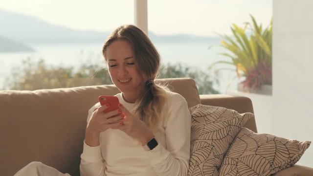 Smiling woman using smartphone for chatting in social networks