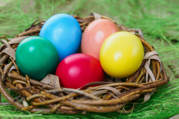 Fototapeta na wymiar multi-colored easter eggs lie in a nest on a green grassy background close-up