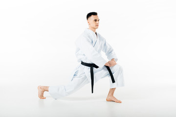 male karate fighter stretching legs isolated on white