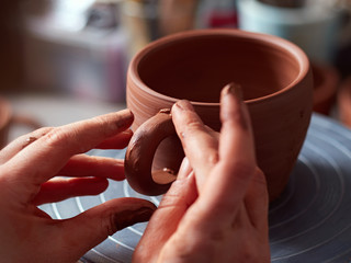 production process of pottery. The potter joins the cup and the handle from the cup.