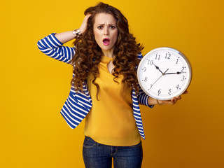 stressed trendy woman on yellow background showing clock