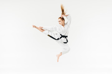 Female karate fighter jumping isolated on white © LIGHTFIELD STUDIOS