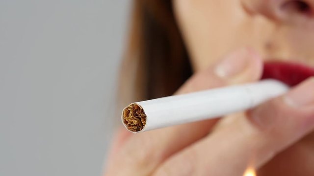 young brunette woman lights the cigarette, slow motion