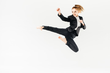 businesswoman screaming, jumping and performing kick in suit isolated on white
