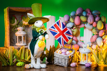 The Feast of Easter. Rabbit with colorful eggs. Holiday of Easter in England. The flag of England is held by the Easter bunny.