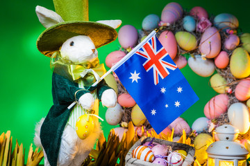 The Feast of Easter. Rabbit with colorful eggs. Holiday of Easter in Australia. A flag of Australia is holding an Easter bunny.