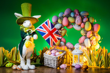 Fototapeta premium The Feast of Easter. Rabbit with colorful eggs. Holiday of Easter in England. The flag of England is held by the Easter bunny.