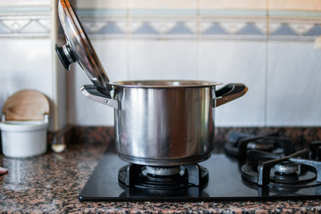 Fotografía de una olla de plata en los fogones de una cocina de casa.