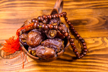 Date fruits and rosary on wooden table