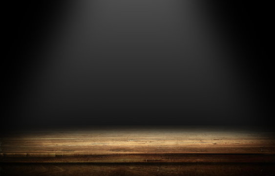 Wood table in dark room with light background.
