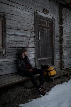 Man sitting outside wooden cabin