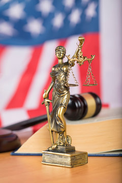 Statue of Themis and judge's gavel on a table.