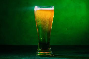 close-up view of glass with fresh cold amber beer on green