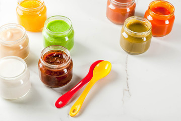 Variety of homemade baby vegetable and fruit puree,  white marble background copy space
