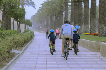 Naklejka premium father with children ride bikes on city alley