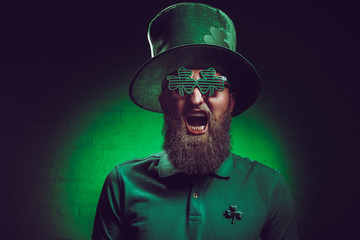 bearded man in green irish hat and funny eyeglasses screaming at camera