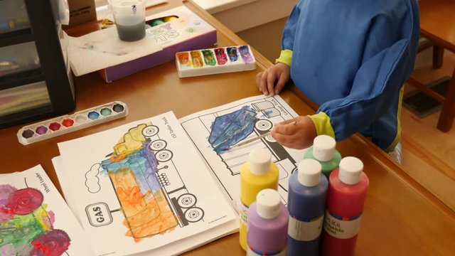 Cute little boy painting tractors at a craft table