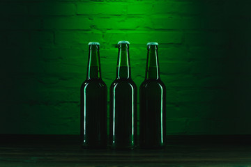 close-up view of green bottles of beer near green brick wall