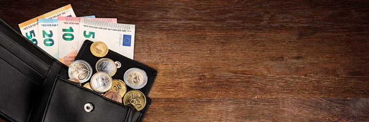 Fotobehang euro coin and bank note in black  leather wallet on wide wood wooden panorama business finance background with copy space  © stockphoto-graf