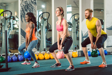 Gruppe von Männern und Frauen bei Fitness Training mit Kettlebell 
