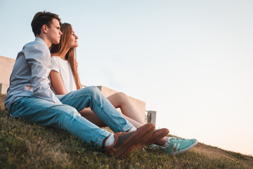 Couple sitting on the hill  in city at sunset