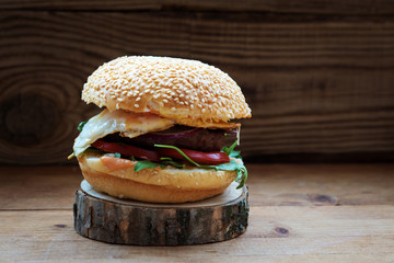 juicy delicious Burger with arugula and egg on wooden background