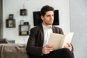 Serious young businessman sitting in home