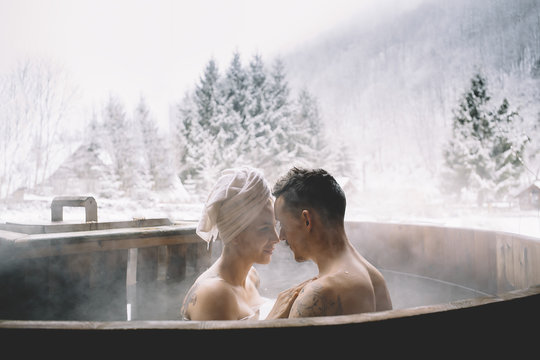 Couple sitting in plunge tub in winter