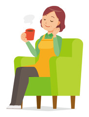A middle-aged housewife wearing an apron is sitting on a sofa and drinking coffee