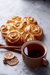 Homemade rose bread, cup of tea, dried citrus and spicies on white textured background, close-up, shallow depth of field
