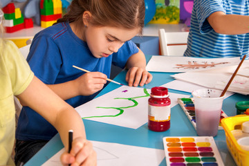 Small students painting in art school class. Child drawing by paints on table. Boy and girls in kindergarten. Drawing education develops creative abilities of children. Art children's school. © Gennadiy Poznyakov