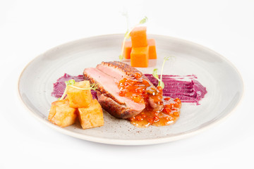 Roast duck breast, red cabbage with apple, roasted potatoes,mountain ash and honey sauce on a white background