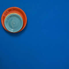 Still life - red, turquoise and green dishes stand in the corner of a blue background