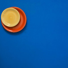 Still life - red and yellow dishes stand in the corner of a blue background