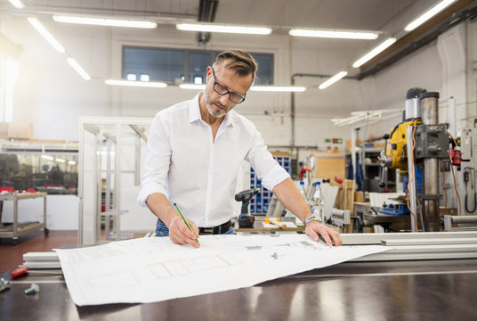 Mature businessman in factory working on plan