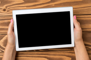 Woman holding digital tablet over wooden table.