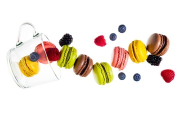 colorful traditional French sweets macaroons from almond flour and fresh berries  isolated on white. and an empty tea cup. objects in motion