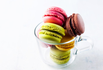 colorful, bright, traditional French macaroon cookies sweetness of almond flour in a transparent coffee cup. food background for confectionery, Bakery and bars.