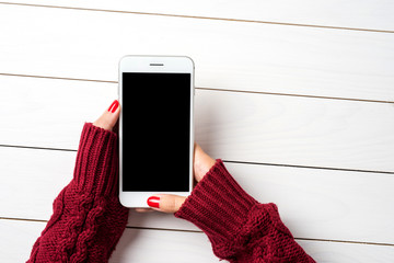 Woman using a smartphone in warm sweater. Top view