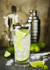 Mojito cocktail with lime and mint in glass on a stone table. Bar tools and ingredients for cocktail.