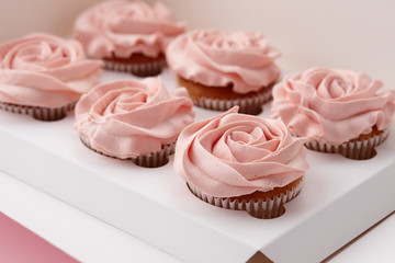 Muffins or cupcakes with flower shaped cream in box, close up view