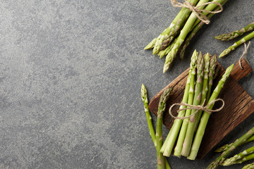 Bunch of fresh green asparagus on dark wooden background, top view
