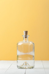 Empty glass bottle for rum on a light white-yellow background..