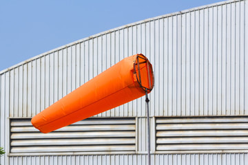 orange wind sock in front of the factory, wind measurement equipment